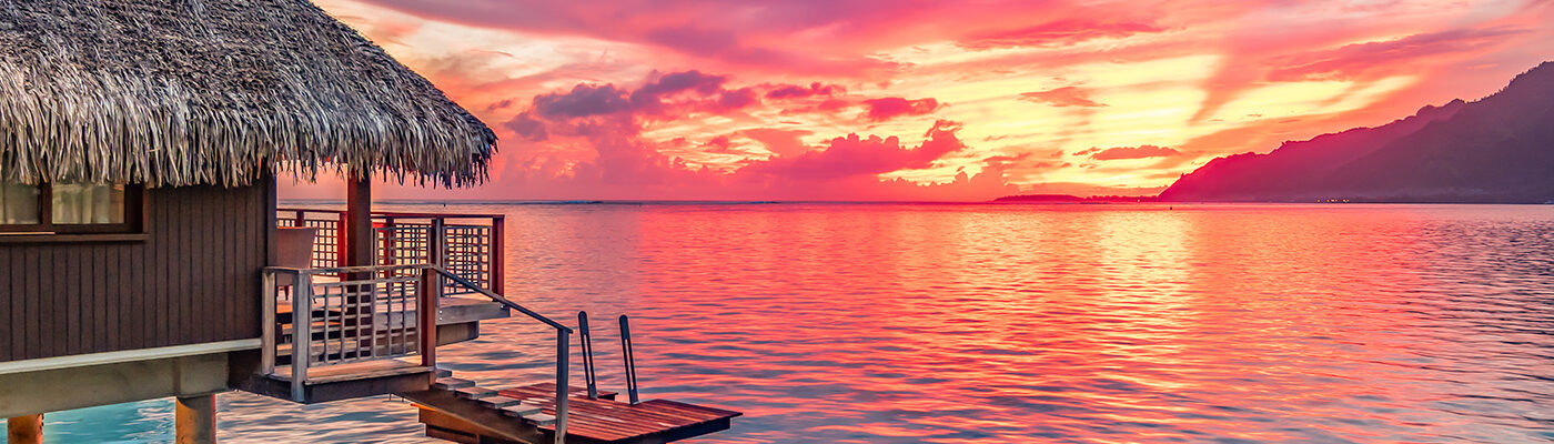 View of overwater bungalow at sunset