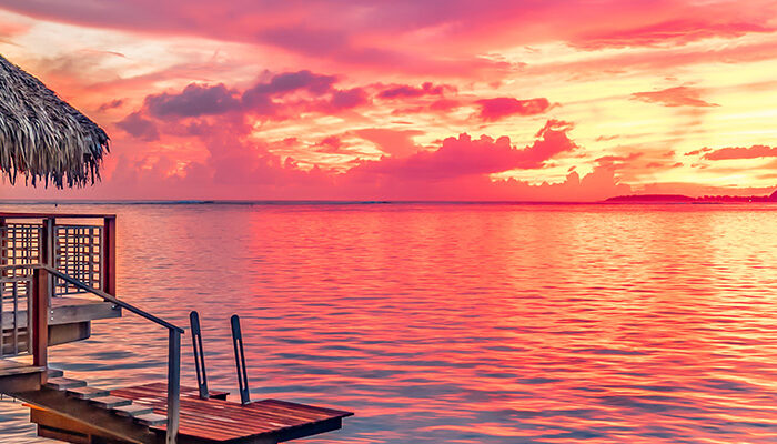 View of overwater bungalow at sunset