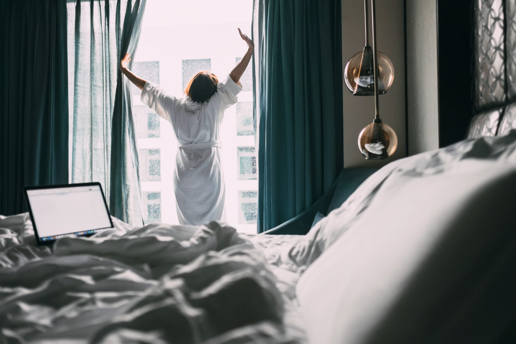 Woman stretching in front of hotel room window in the morning light