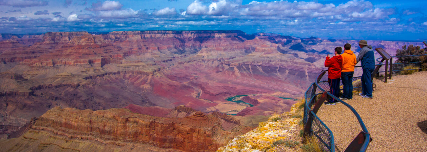 Three people admiring the vista at a Grand Canyon lookout point