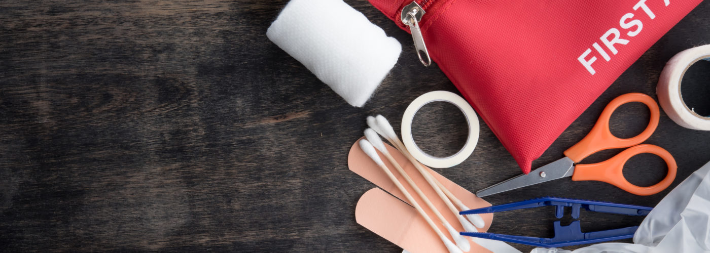 First aid kit and supplies on a dark wood backdrop