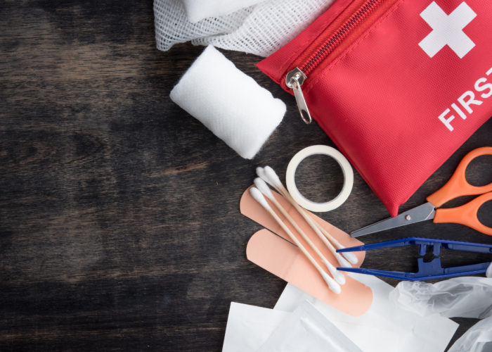 First aid kit and supplies on a dark wood backdrop