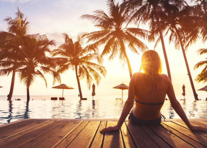 Woman relaxing on a pier in front of a pool and palm trees