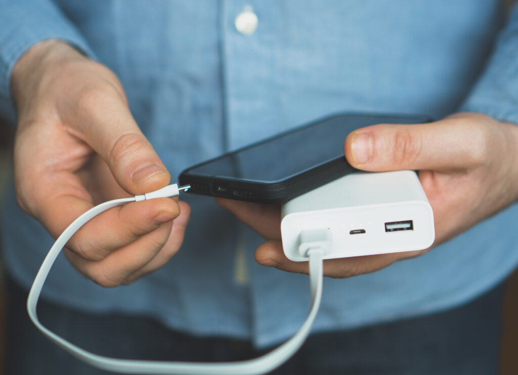 Close up of person plugging phone into portable battery pack