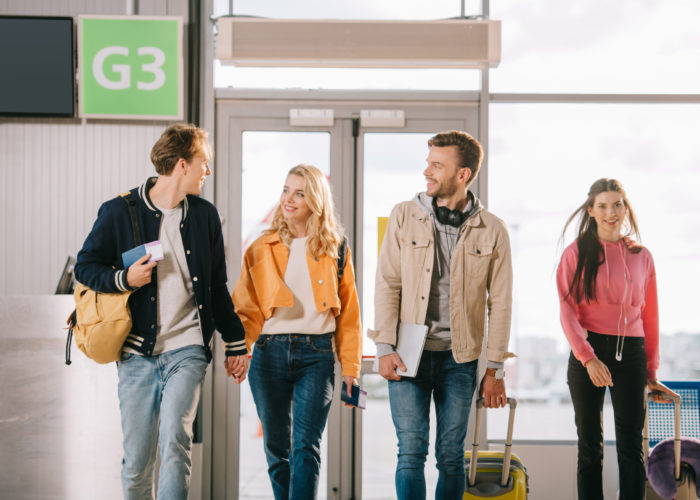 Four friends walking to an airport terminal