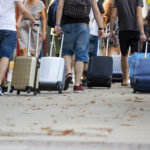 People pulling rolling suitcases in large crowd