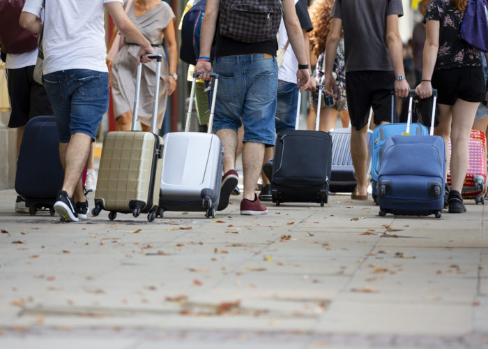 People pulling rolling suitcases in large crowd