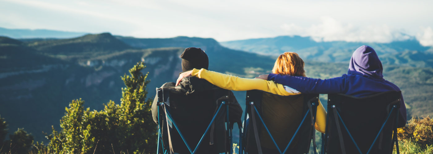 Three friends sitting on camping chairs and looking at a view of the mountains