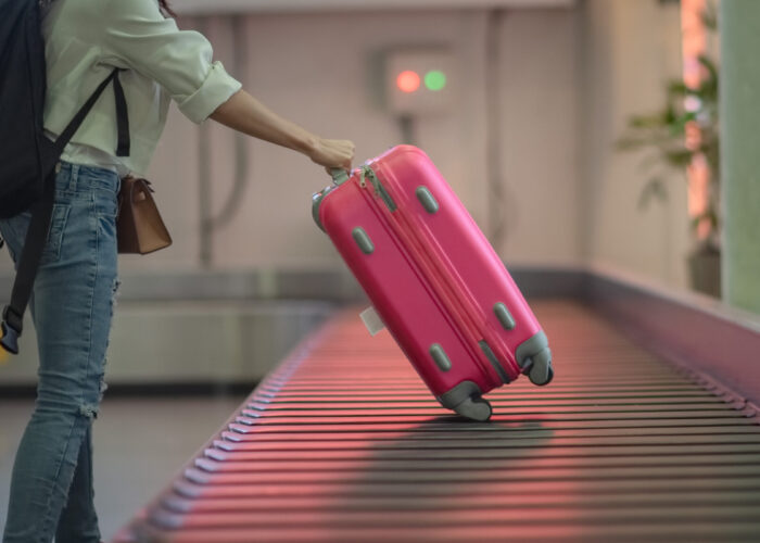 Person collecting the last suitcase from an empty baggage carousel in the airport