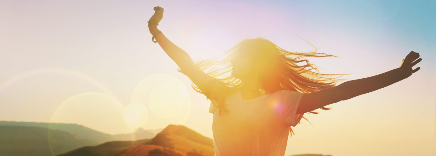 Twirling woman backlit by sunset