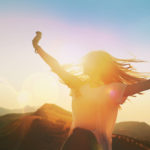 Twirling woman backlit by sunset