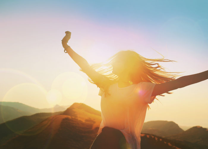 Twirling woman backlit by sunset