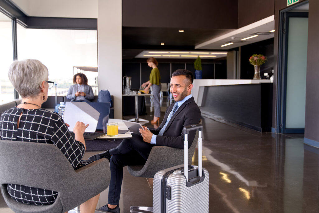 A group of people sitting, working, and talking in an airport lounge