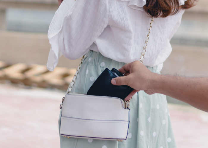 Hand sneaking into frame of photo to steal wallet from bag of unsuspecting tourist