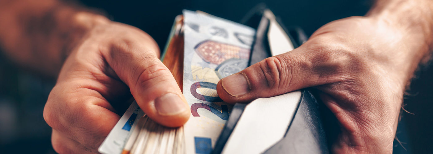 Close up of hands leafing through a wallet full of euros