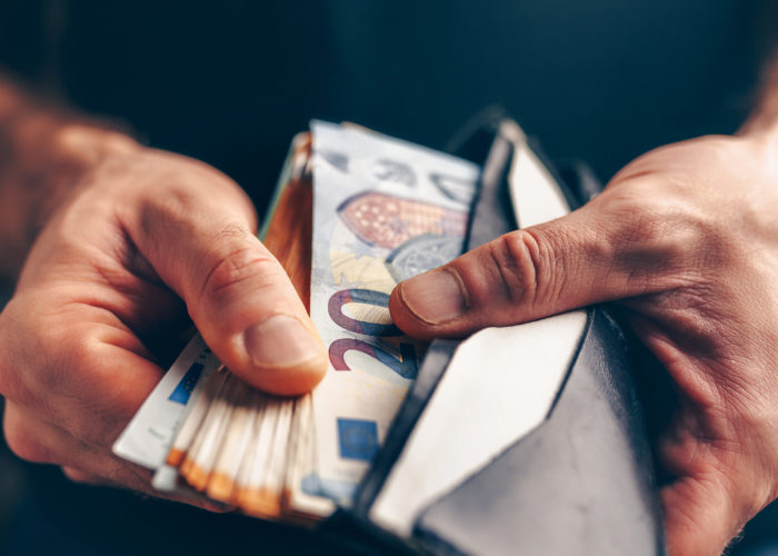 Close up of hands leafing through a wallet full of euros