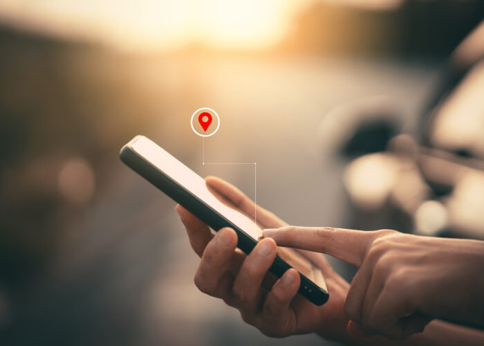 Close up of person using their smartphone with a graphic overlayed showing a location pin