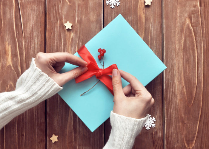 Aerial view of woman tying a red ribbon on a blue box