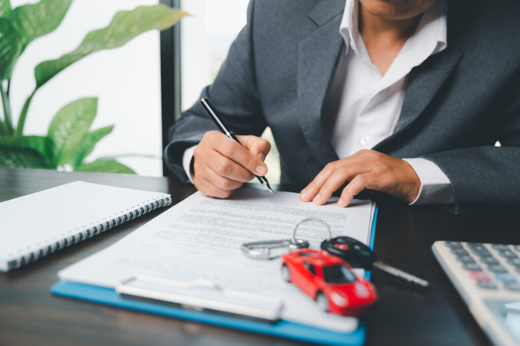 Person signing car rental documents at a desk