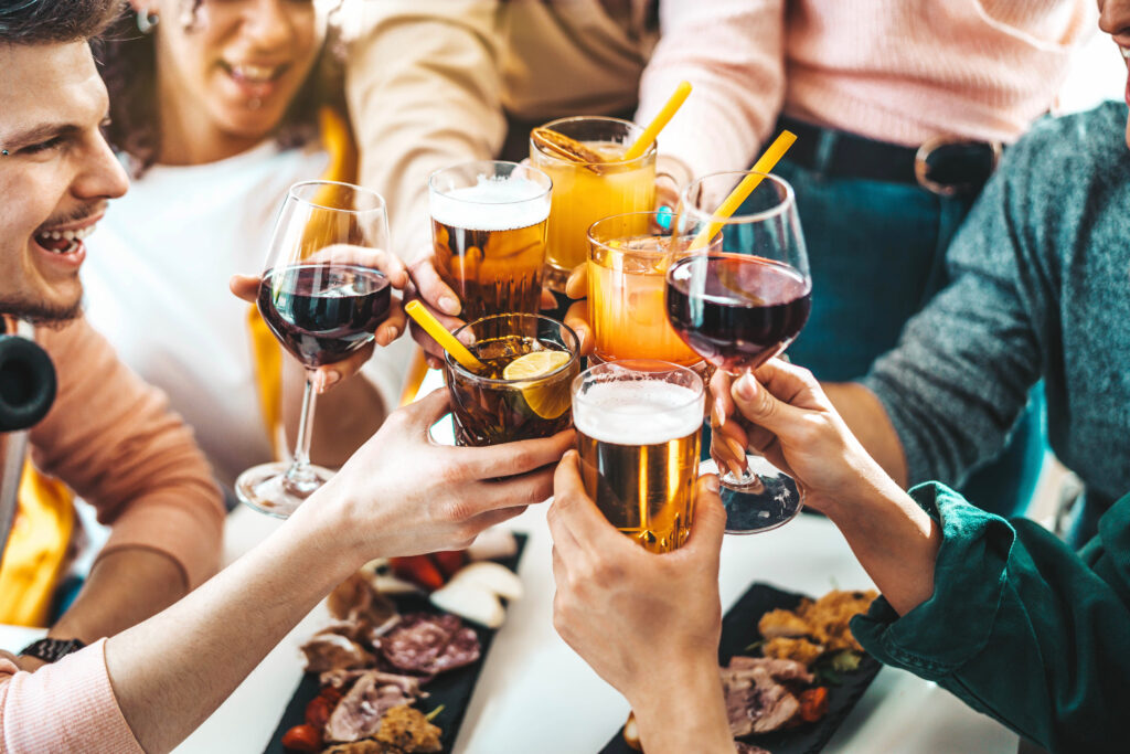 Close up of group of friends clinking glasses together at dining table