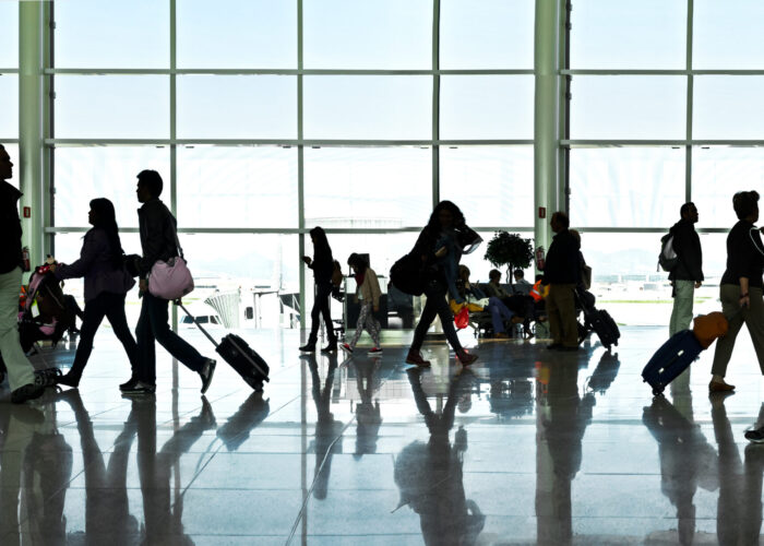 Silhouettes of people walking past a large window in an airport terminal