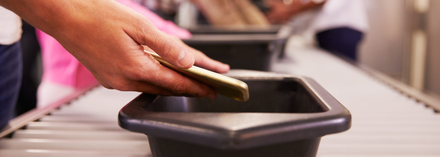 Close up of hands putting smartphone in security bin