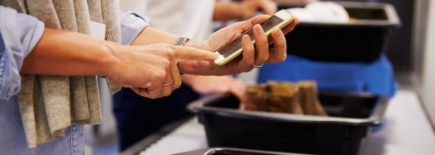 Person placing smartphone into bin at airport security