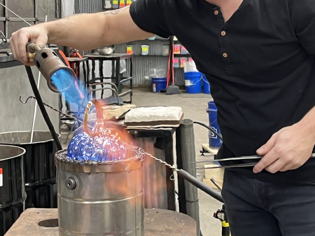 Person firing a glass pumpkin at a class at Jack Pine Studio in Logan, Ohio, United States