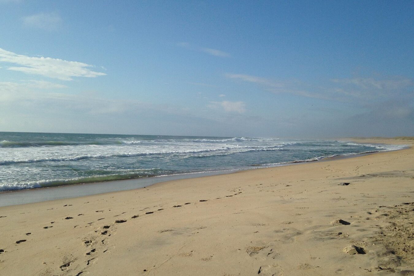 Empty Lighthouse Beach, Buxton, Outer Banks of North Carolina with waves coming on the white sand.