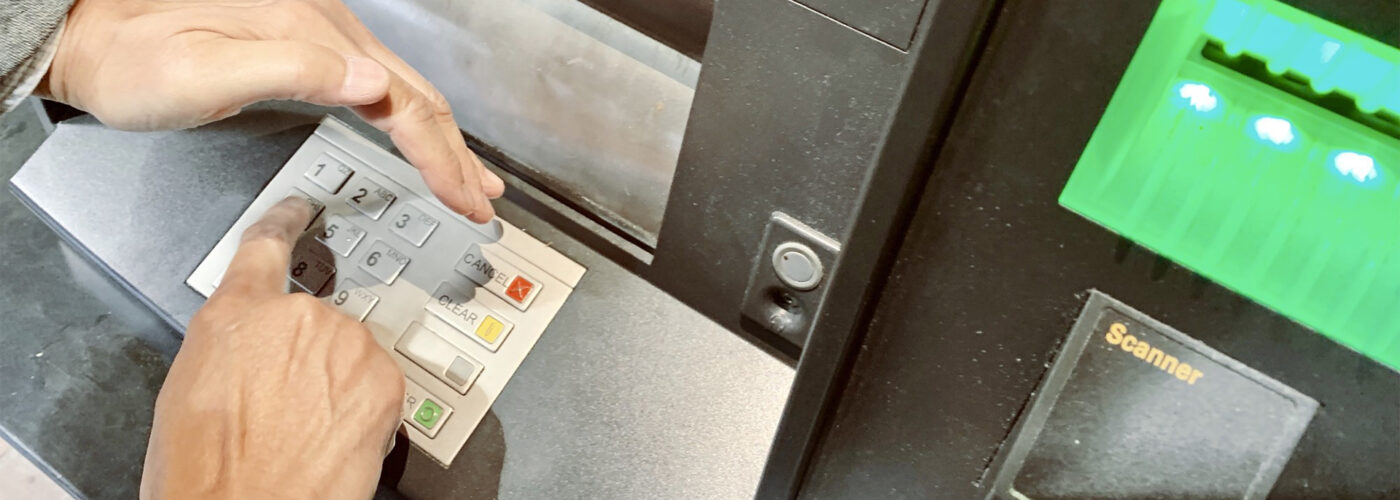 foreign transaction fees photo of person covering PIN number on ATM.