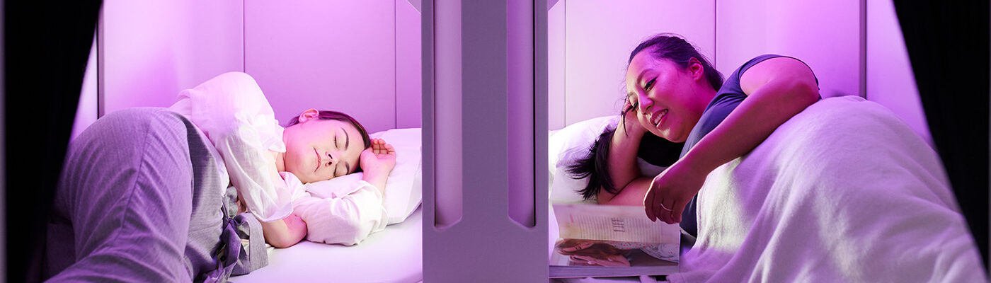 People resting in Sky Nest, lay-flat economy seats on Air New Zealand that resemble bunk beds