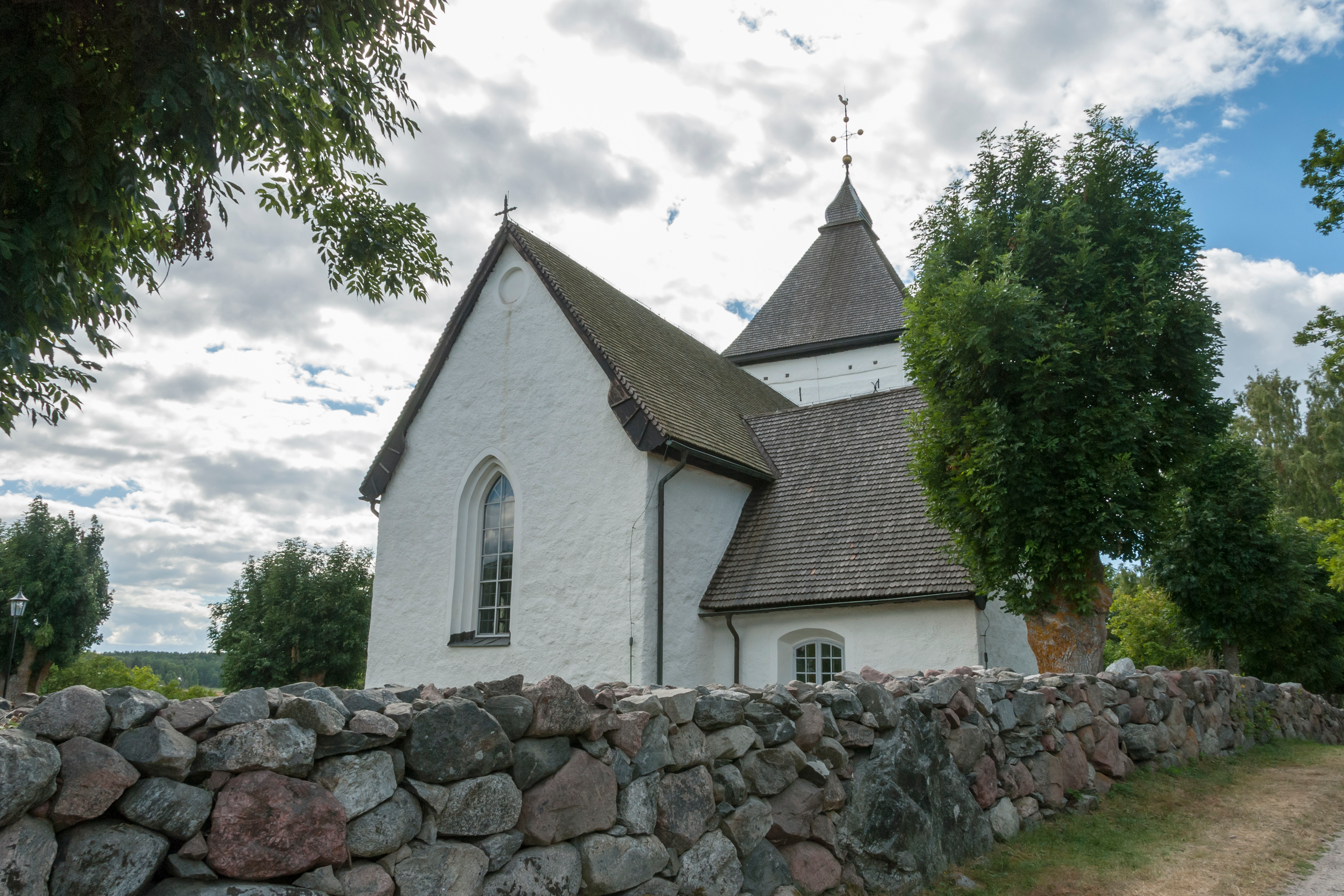Old church in Hovgarden Sweden with rock wall in front.