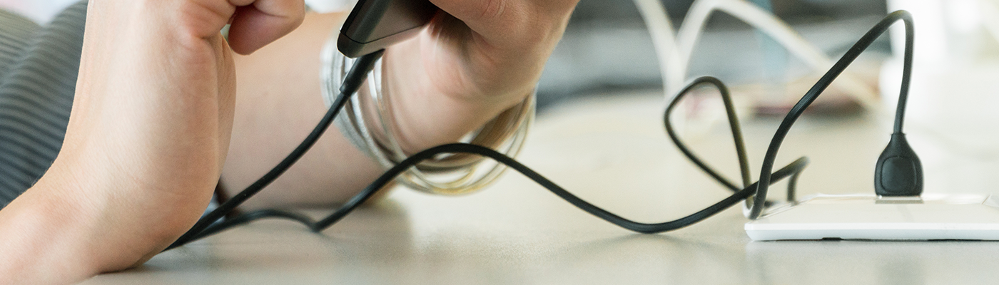 Close up of person plugging in phone to public charging station