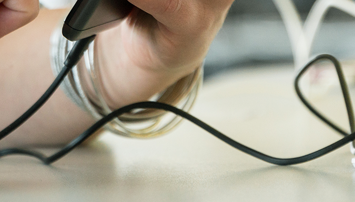 Close up of person plugging in phone to public charging station